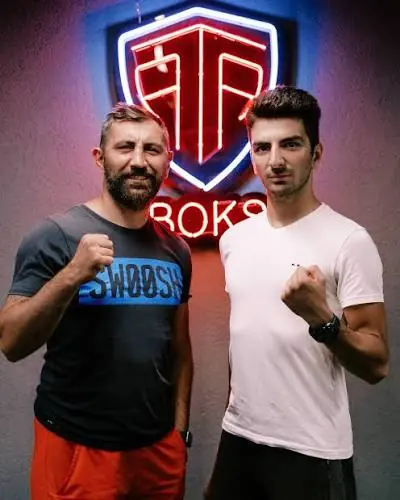 Arda Tamer Avcı (solda) ATA Boks salonundaki neon ATA tabelasının önünde